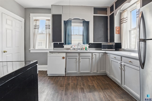 kitchen with baseboards, dark wood-style floors, light countertops, a sink, and stainless steel appliances