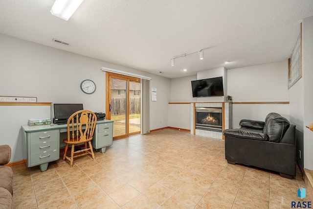 home office with track lighting, a tile fireplace, light tile patterned floors, a textured ceiling, and baseboards