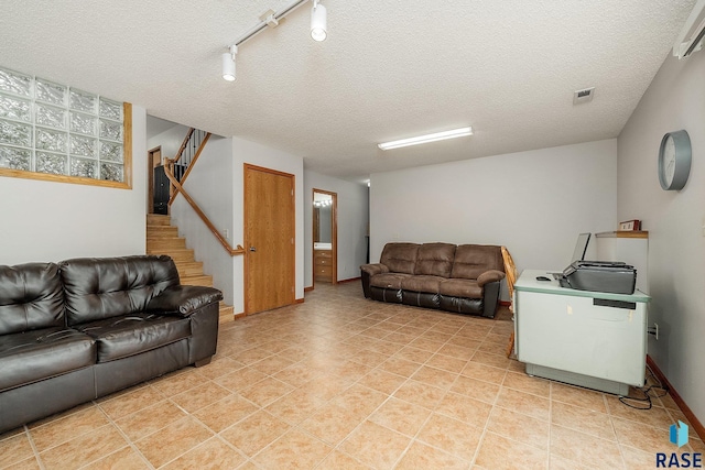 living area with stairway, rail lighting, a textured ceiling, and light tile patterned floors