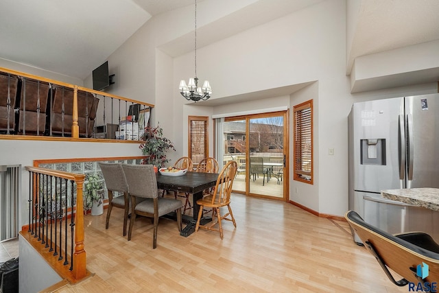 dining room with light wood finished floors, a chandelier, stairs, high vaulted ceiling, and baseboards