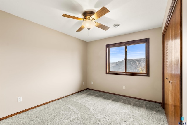 unfurnished bedroom featuring a closet, baseboards, a ceiling fan, and carpet
