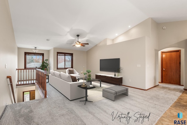 living area with high vaulted ceiling, arched walkways, baseboards, and a ceiling fan