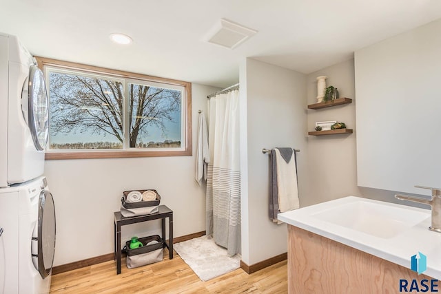 1000 N Six Mile Rd, Sioux Falls, SD 57110 - bathroom with visible vents, baseboards, a sink, stacked washing maching and dryer, and wood finished floors
