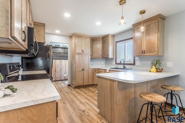 1000 N Six Mile Rd, Sioux Falls, SD 57110 - kitchen featuring light wood-style floors, a kitchen breakfast bar, a peninsula, appliances with stainless steel finishes, and a sink