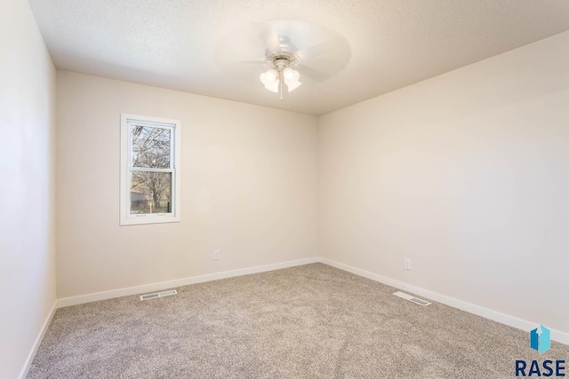 empty room featuring ceiling fan, visible vents, and carpet floors