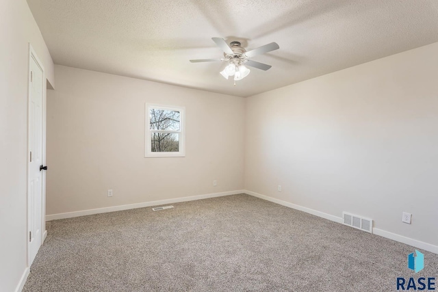 carpeted spare room featuring a textured ceiling, ceiling fan, baseboards, and visible vents