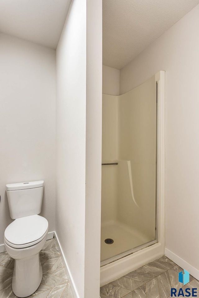 full bathroom featuring a shower stall, marble finish floor, baseboards, and toilet