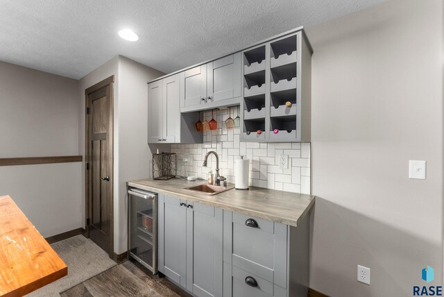 5320 S Solono Ave, Sioux Falls, SD 57108 - kitchen with dark wood-style flooring, a sink, wine cooler, decorative backsplash, and gray cabinetry