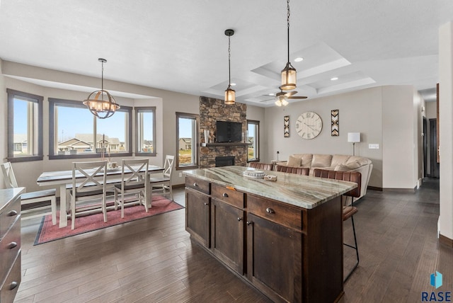 5320 S Solono Ave, Sioux Falls, SD 57108 - kitchen featuring dark brown cabinets, a stone fireplace, a kitchen breakfast bar, and dark wood finished floors