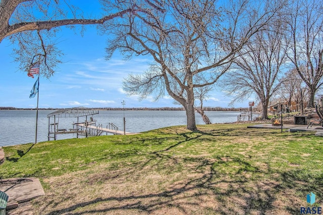 view of yard featuring a water view, boat lift, and a dock