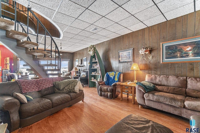 living area featuring wooden walls, stairway, and wood finished floors