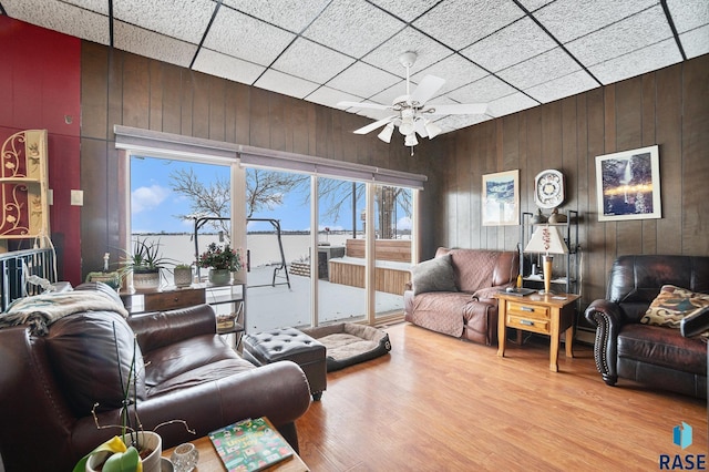 living area with wood walls, a ceiling fan, and wood finished floors