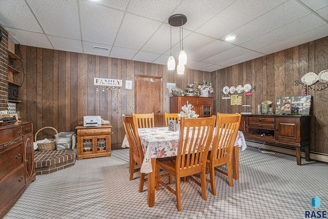 dining space with wooden walls, visible vents, and carpet floors