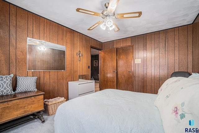 bedroom featuring wood walls, a ceiling fan, and carpet floors