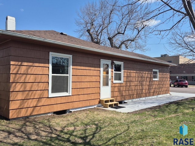 back of property featuring entry steps, a chimney, and a yard