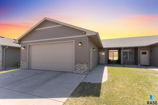 ranch-style home with a garage, stone siding, a front lawn, and concrete driveway