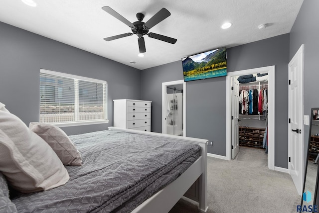 bedroom with a spacious closet, a ceiling fan, light carpet, a closet, and baseboards