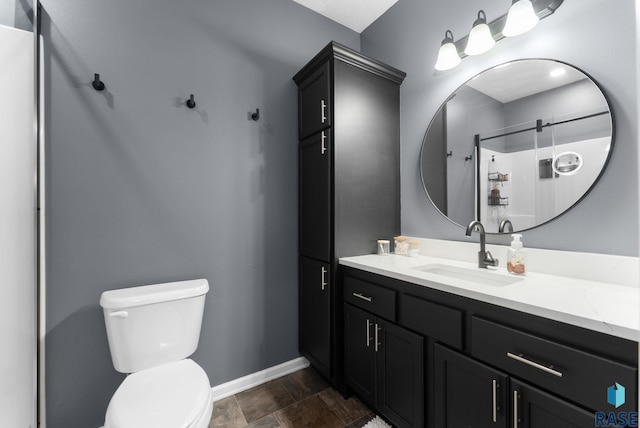 bathroom with vanity, toilet, a shower with shower door, and baseboards