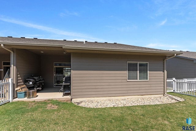back of property featuring fence, a patio area, and a yard