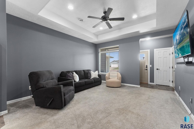 carpeted living area featuring a tray ceiling, a ceiling fan, baseboards, and recessed lighting