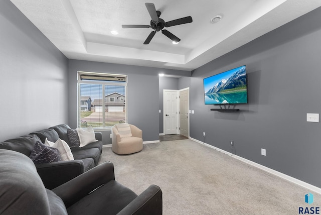 living area with ceiling fan, baseboards, carpet, and a raised ceiling