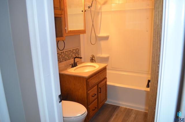 full bath featuring tasteful backsplash, wood finished floors, vanity, washtub / shower combination, and toilet