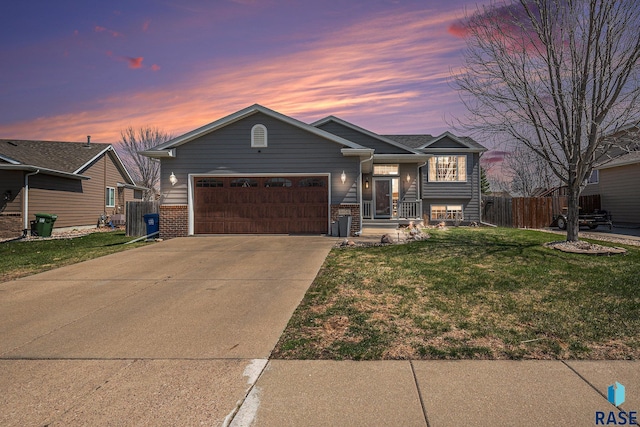 view of front of home featuring fence, a front lawn, concrete driveway, an attached garage, and brick siding