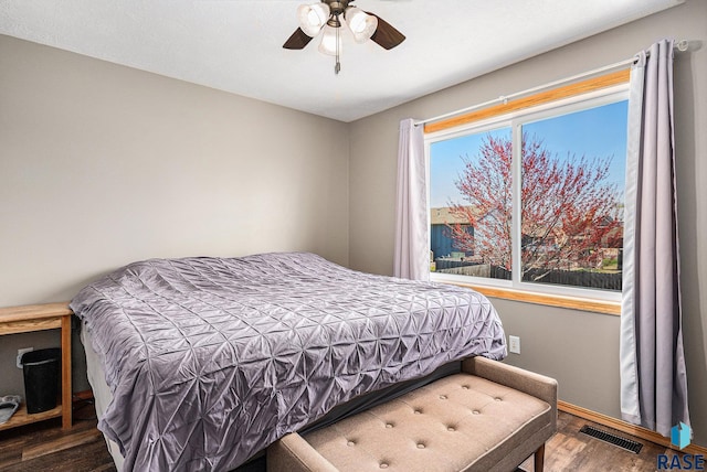bedroom featuring wood finished floors, visible vents, a ceiling fan, and baseboards