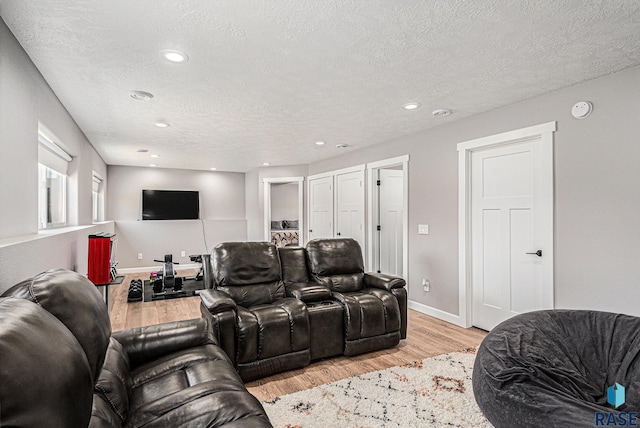 cinema with recessed lighting, light wood-style flooring, a textured ceiling, and baseboards