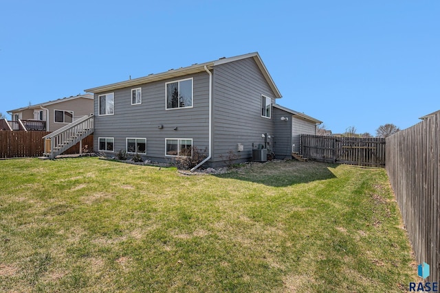 back of house featuring a fenced backyard, a yard, and cooling unit
