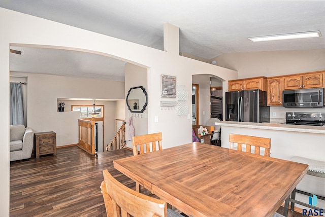 dining room with arched walkways, dark wood finished floors, and lofted ceiling