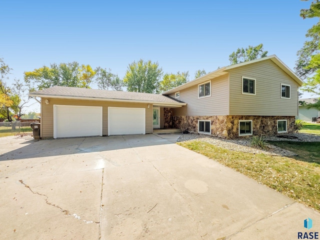 47205 94th St, Sioux Falls, SD 57108 - tri-level home featuring driveway, fence, stone siding, and a garage