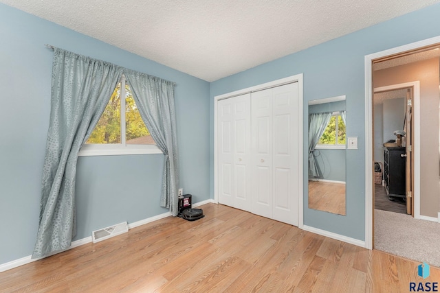 47205 94th St, Sioux Falls, SD 57108 - unfurnished bedroom with a textured ceiling, baseboards, visible vents, wood finished floors, and a closet