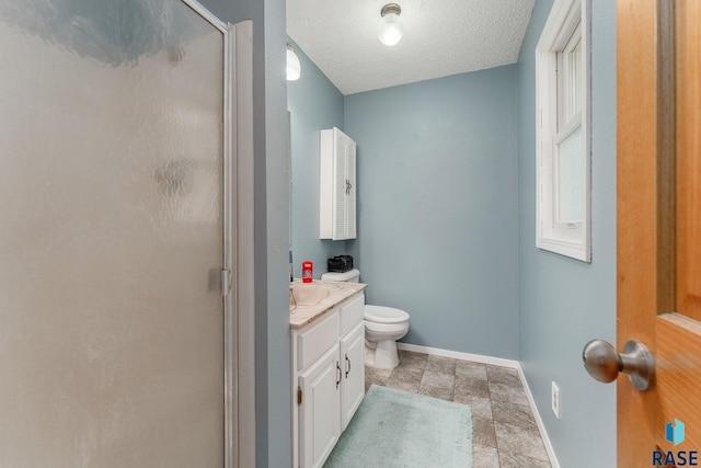 47205 94th St, Sioux Falls, SD 57108 - bathroom featuring toilet, vanity, stone finish flooring, baseboards, and a stall shower