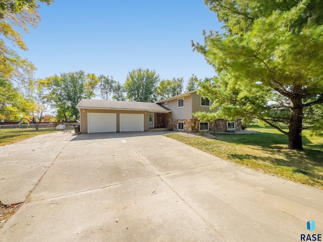 47205 94th St, Sioux Falls, SD 57108 - tri-level home with stone siding, concrete driveway, fence, a garage, and a front yard