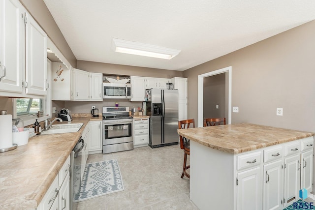 47205 94th St, Sioux Falls, SD 57108 - kitchen featuring light countertops, a sink, white cabinetry, and appliances with stainless steel finishes
