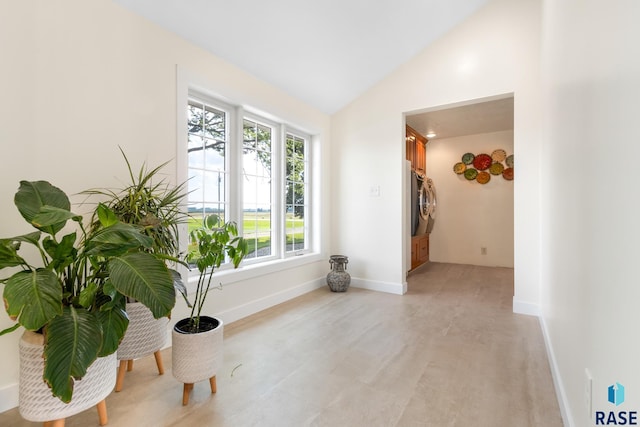 interior space featuring vaulted ceiling, baseboards, and washer and clothes dryer