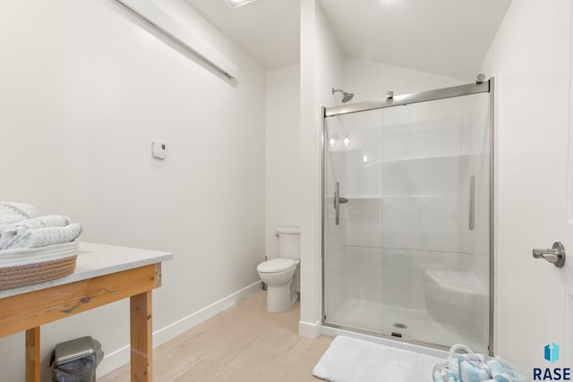 full bath with a stall shower, toilet, baseboards, wood finished floors, and vanity