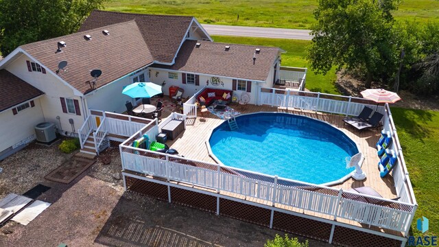 view of pool with a fenced in pool, central AC, and a deck