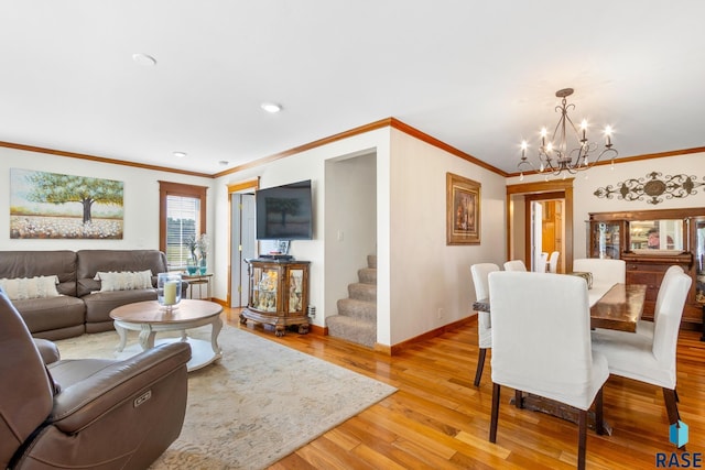 living area featuring a chandelier, light wood-type flooring, baseboards, and ornamental molding