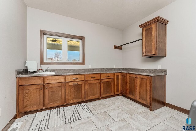 interior space featuring dark countertops, a sink, brown cabinetry, baseboards, and visible vents
