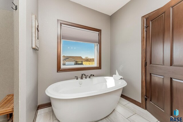 bathroom with baseboards, a freestanding tub, and tile patterned flooring