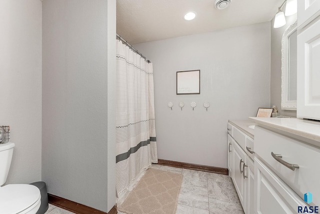 bathroom with toilet, vanity, visible vents, and baseboards
