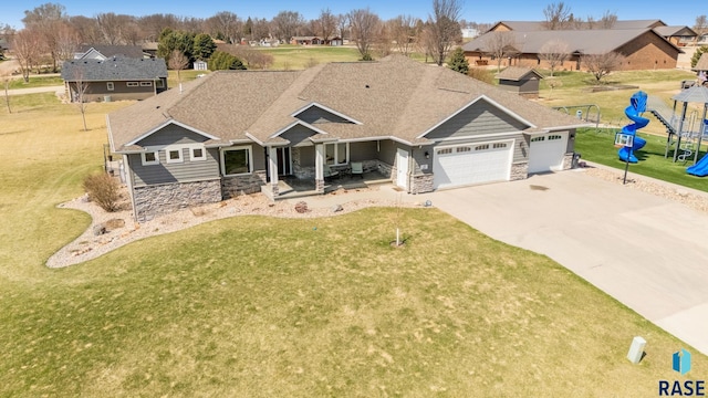 view of front of property with concrete driveway, a front lawn, stone siding, covered porch, and an attached garage