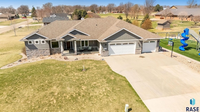 view of front facade with a playground, concrete driveway, a front lawn, stone siding, and a garage