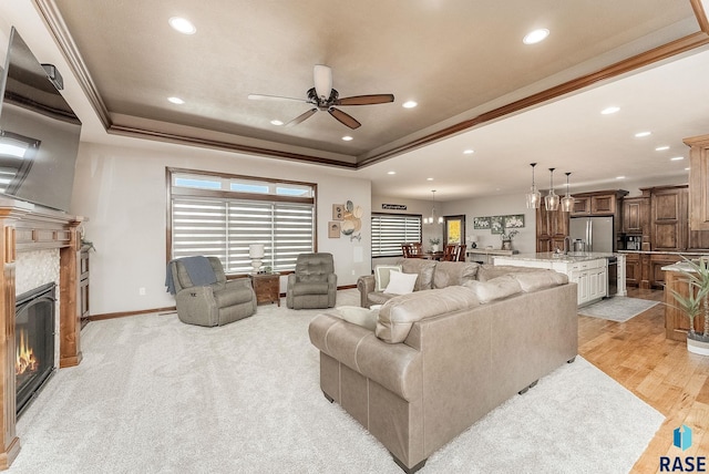 living room with baseboards, a tray ceiling, recessed lighting, and ceiling fan