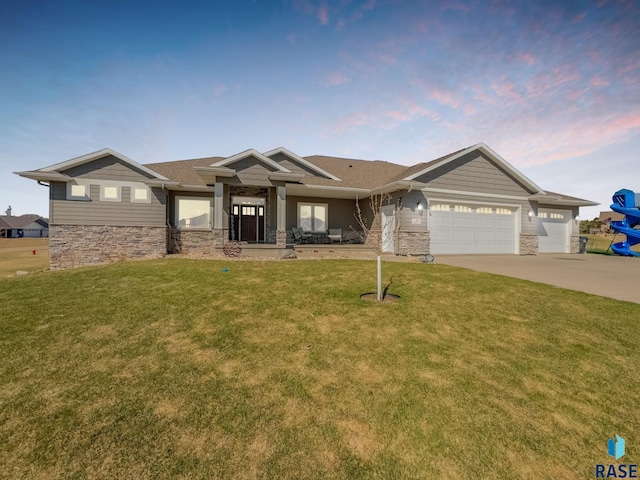 craftsman house with stone siding, driveway, a yard, and a garage