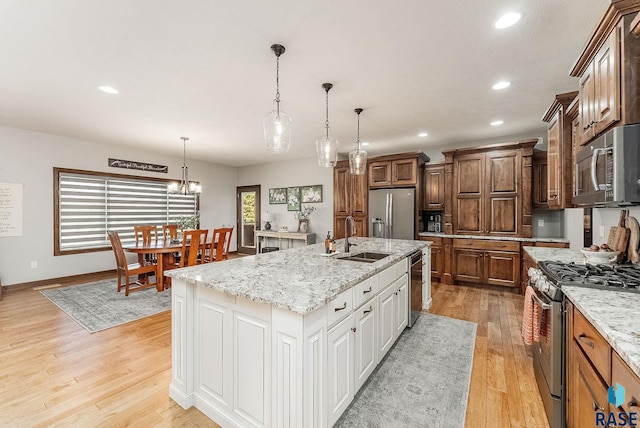 kitchen featuring stainless steel appliances, a kitchen island with sink, a sink, light wood-type flooring, and recessed lighting