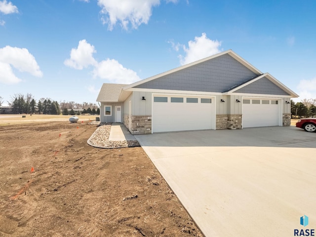 craftsman inspired home featuring a garage, stone siding, concrete driveway, and board and batten siding