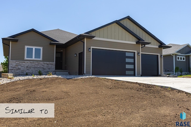 craftsman house with concrete driveway, an attached garage, board and batten siding, stone siding, and roof with shingles